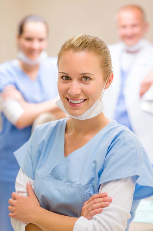 Bilden visar 3 tandvårdspersonal där en av de står längst fram med ett leende på läpparna.